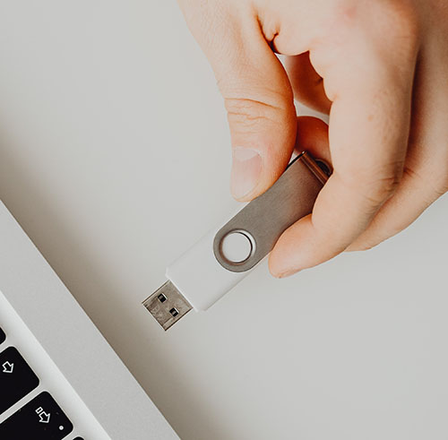 Photographie d'une clef usb blanche qui s'apprête à être branché à un ordinateur